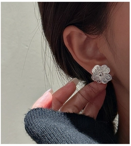 Macro detail of S925 sterling silver floral stud earring with textured petals on model