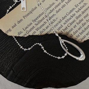 S925 sterling silver bead chain necklace with hollow oval pendant on stone background
