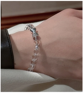 Detail of S925 sterling silver bow charm and clear crystal bead bracelet on wrist