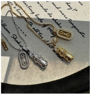 Macro detail of S925 silver and gold vajra pestle necklaces with pi xiu charms