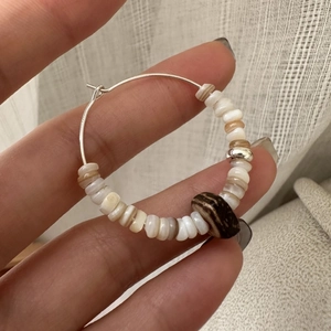 Handheld S925 silver hoop earrings with natural shell beads in warm earthy tones