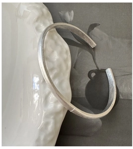 Detail of minimalist S925 sterling silver cuff bangle with matte brushed metal finish