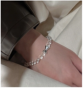 Close-up of S925 silver bow bracelet with clear crystal beads on a model wrist