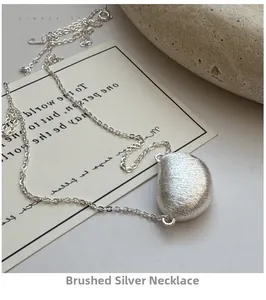 Detail van de minimalistische S925 zilveren boon hanger met geborstelde textuur en O-ketting