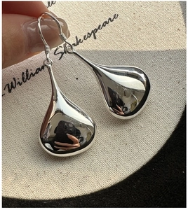 Macro shot of silver teardrop earrings with a high-polish mirror finish on a hook design
