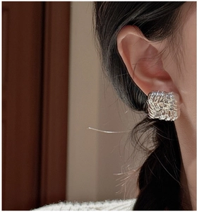Close-up of S925 silver stud earrings with a textured woven rectangular design on the ear