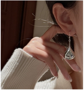 Close-up of polished S925 sterling silver teardrop earrings on a model for daily wear