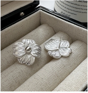 Macro view of S925 silver five-petal flower earrings with textured petals in a gift box