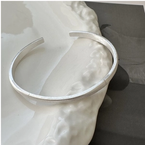 Macro detail of minimalist S925 sterling silver open bangle with brushed matte texture