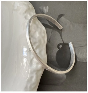 Close-up of minimalist S925 sterling silver cuff bracelet with a brushed matte finish