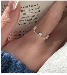 Detail of silver S925 bow-shaped knuckle ring on hand with a cozy vintage background