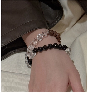 Detail of S925 silver elastic bracelet with clear crystal and brown wooden beads on a wrist