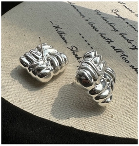 Macro detail of S925 sterling silver earrings with unique pleated texture and knot design