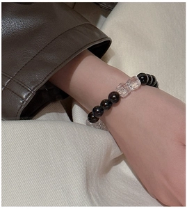 Detail of beaded elastic bracelet with dark wood beads and faceted clear crystal