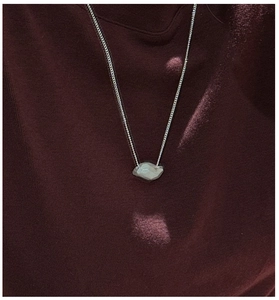 Detail of S925 silver necklace with gray geometric stone pendant on red fabric