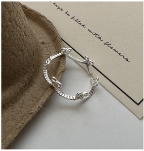 Macro detail of S925 sterling silver bow knot ring with beaded texture on wool fabric