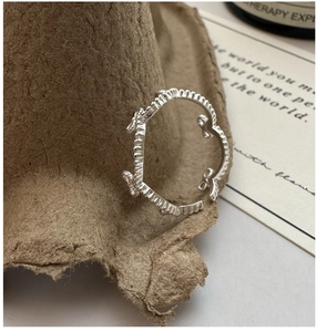 Detailed macro view of S925 sterling silver bow ring with adjustable open band and wavy edge