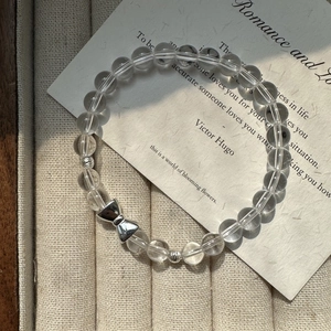 Elegant S925 sterling silver bow bracelet with clear crystal beads on a textured tray
