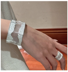Macro detail of S925 silver wide cuff bracelet and ring with irregular lava grid texture