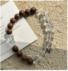 Detail of wooden beads and faceted clear crystal bracelet on a stone surface