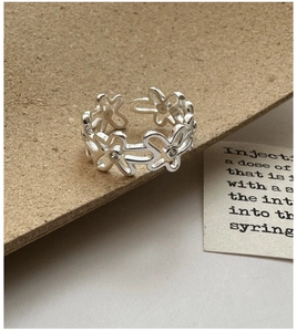 Détail macro d'une bague fleur ajourée en argent avec design ouvert réglable