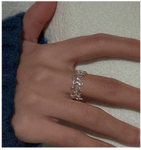 Gros plan d'une bague fleur évidée en argent S925 portée au doigt style vintage