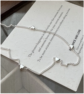 Close-up of S925 sterling silver chain with four 3D heart pendants on a card