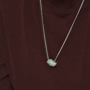 Minimalist S925 sterling silver necklace with irregular pebble pendant on red knitwear