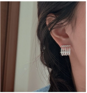 Detail view of silver multi-layer hollow claw earrings worn on a model ear