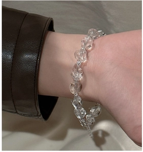 Detail of faceted clear crystal beads on silver bracelet worn with a leather jacket