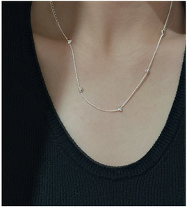 Close-up of a minimalist S925 sterling silver necklace with tiny heart beads on a model