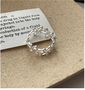 Détail macro d'une bague marguerite vintage en argent S925 sur une surface texturée chaude