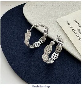 Détail des boucles d'oreilles en argent S925 avec texture de grille creuse et bord ondulé