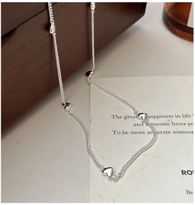 Detail of silver S925 heart necklace draped over a wooden jewelry box and card
