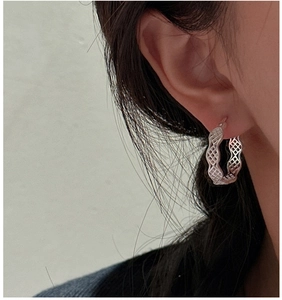 Gros plan de boucles d'oreilles créoles S925 en argent avec maille et bords ondulés