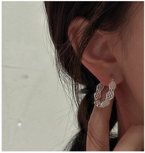 Détail macro d'une boucle d'oreille en argent S925 avec motif mesh texturé ondulé