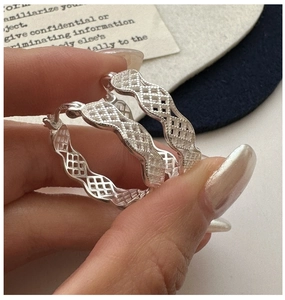 Détail macro de créoles en argent sterling S925 avec motif grille et finition mate brossée