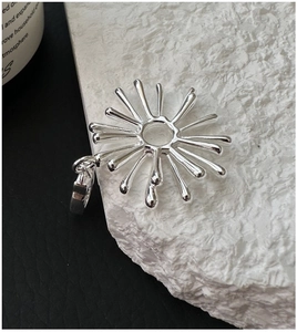 Macro shot of silver sunburst pendant with polished finish on white textured stone