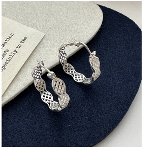 Détail de boucles d'oreilles en argent 925 avec bords ondulés et texture ajourée