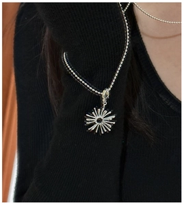 Detail of S925 silver starburst pendant with beaded chain on black knit fabric