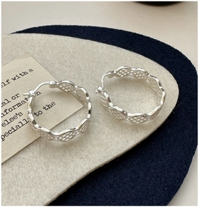 Détail de boucles d'oreilles créoles en argent 925 avec texture maille et bords ondulés