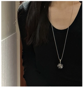 Detailed view of an S925 silver sunflower pendant necklace on a black ribbed sweater