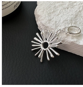 Macro detail of a 925 silver sunburst flower pendant with polished lobster clasp
