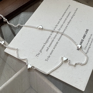 Minimalist S925 sterling silver necklace with heart charms on textured paper