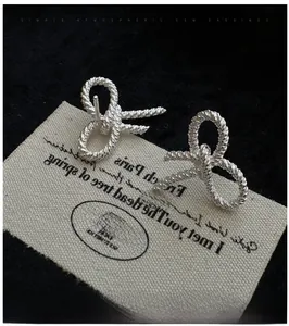 Macro shot of silver bow earrings with twisted texture on black velvet background