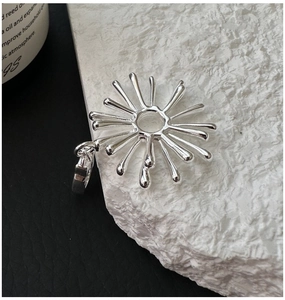 Macro shot of silver sunburst pendant featuring radiating rays on textured stone