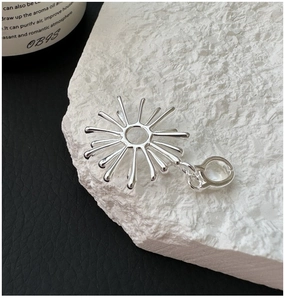 Macro shot of silver sunburst pendant with drop-shaped rays on textured white stone