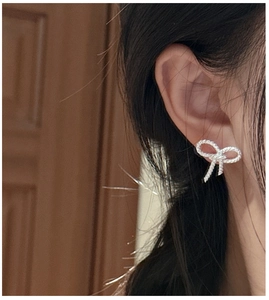 Detailed view of silver bow-shaped stud earrings featuring twisted texture and micropave stones