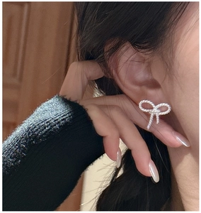 Detail of silver twisted bow earrings on model showing delicate woven texture
