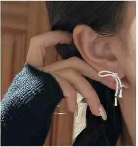 Gros plan de boucles d'oreilles nœud en argent S925 avec glands portées par modèle